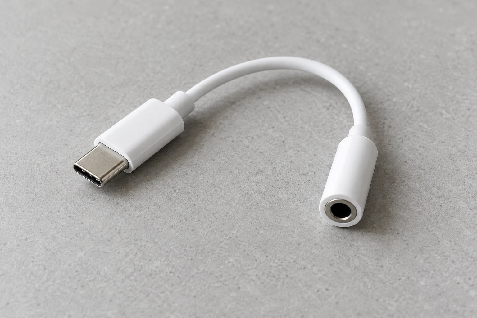 Adaptateur USB-C vers prise jack 3,5 mm blanc posé sur surface grise, câble court